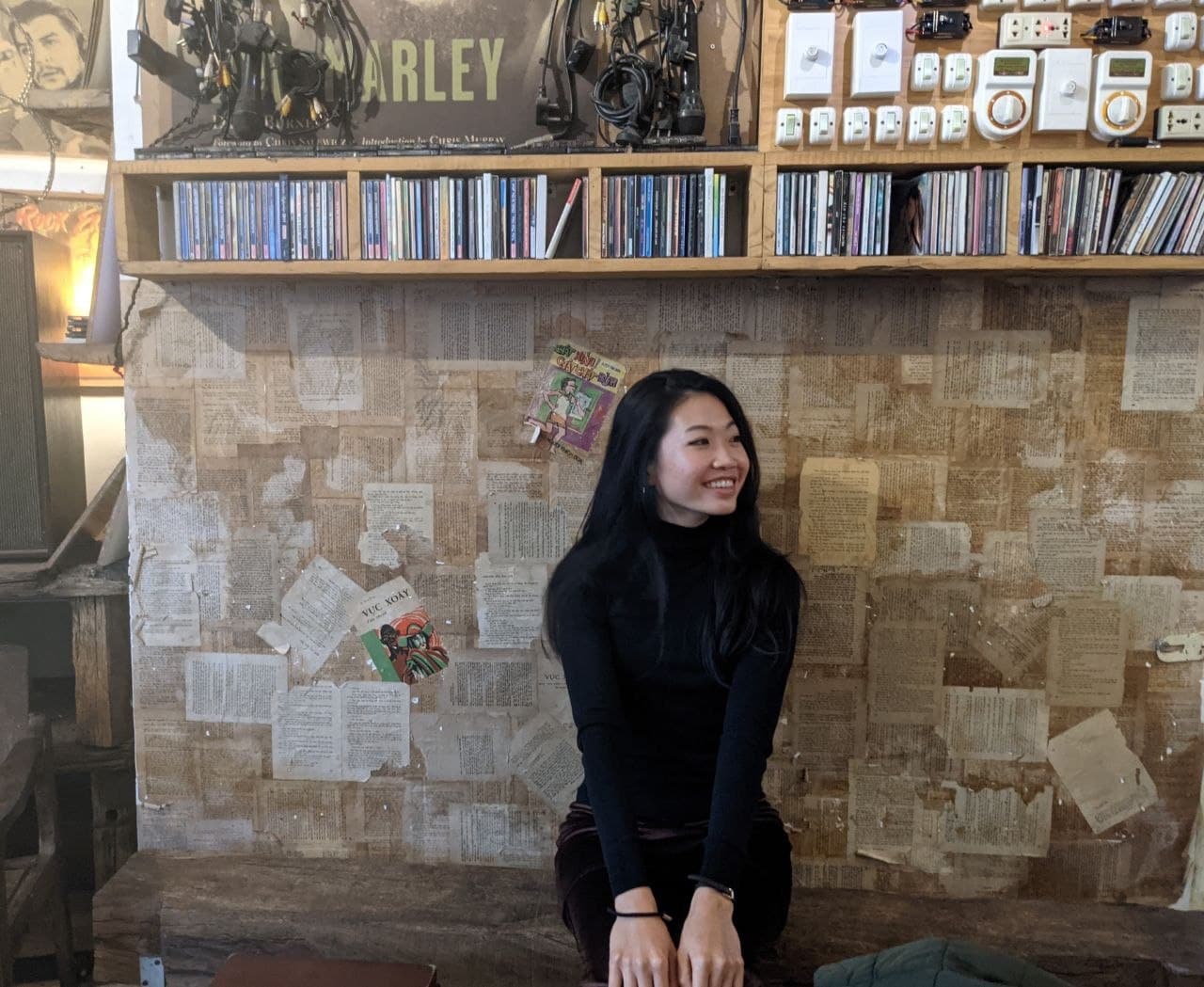Chi Jade Tran sitting in a café lined with books and music